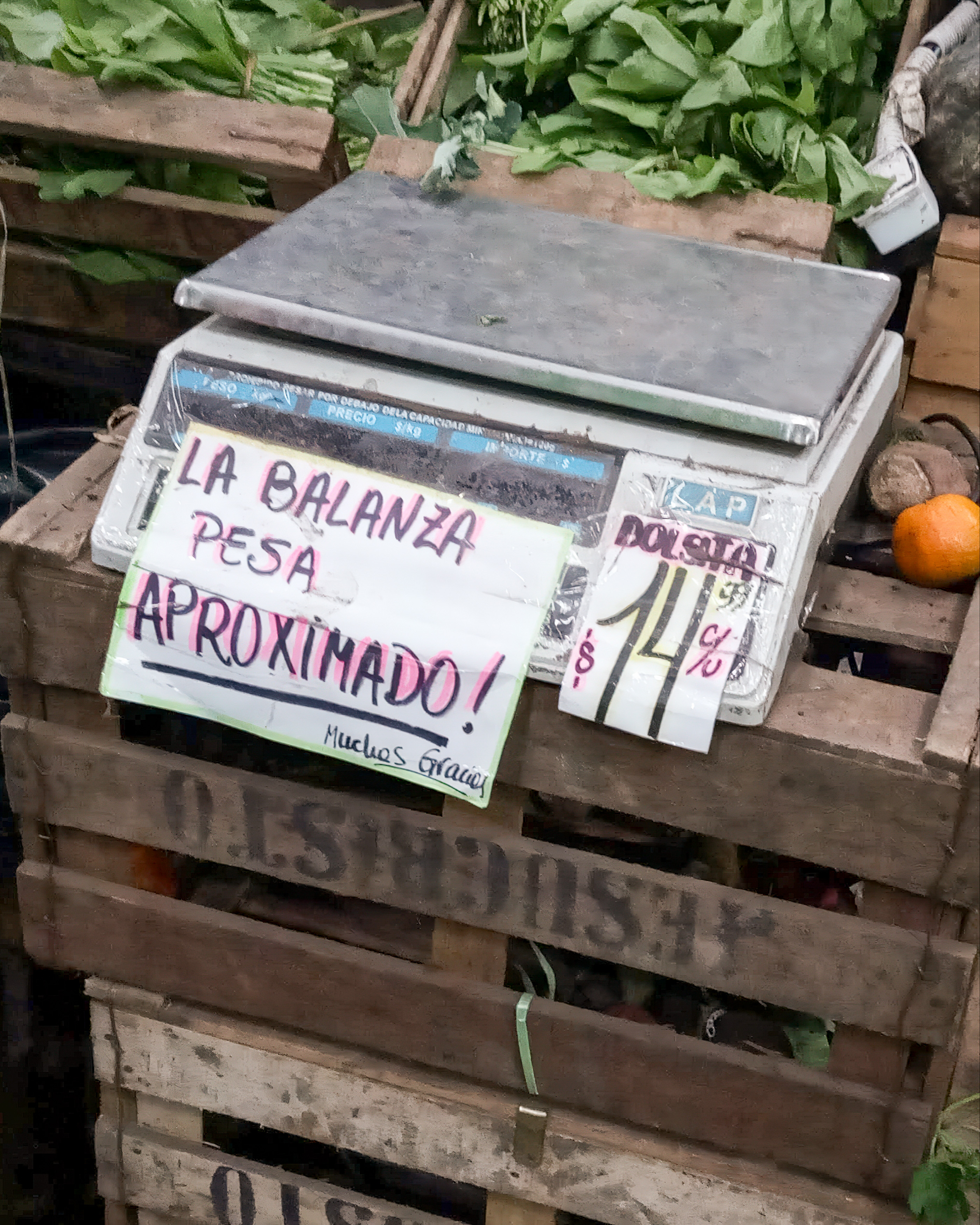 Balanza de verdulería con un cartel manuscrito: La balanza pesa aproximado